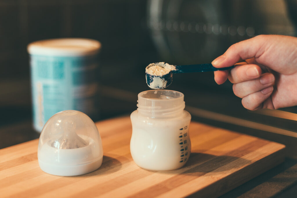 Mother making baby formula in milk bottle